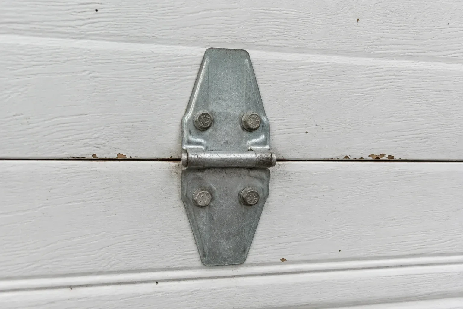 Metal center hinge across a seam in a white sectional garage door. — Garage Door Hinge Replacement, Mississauga